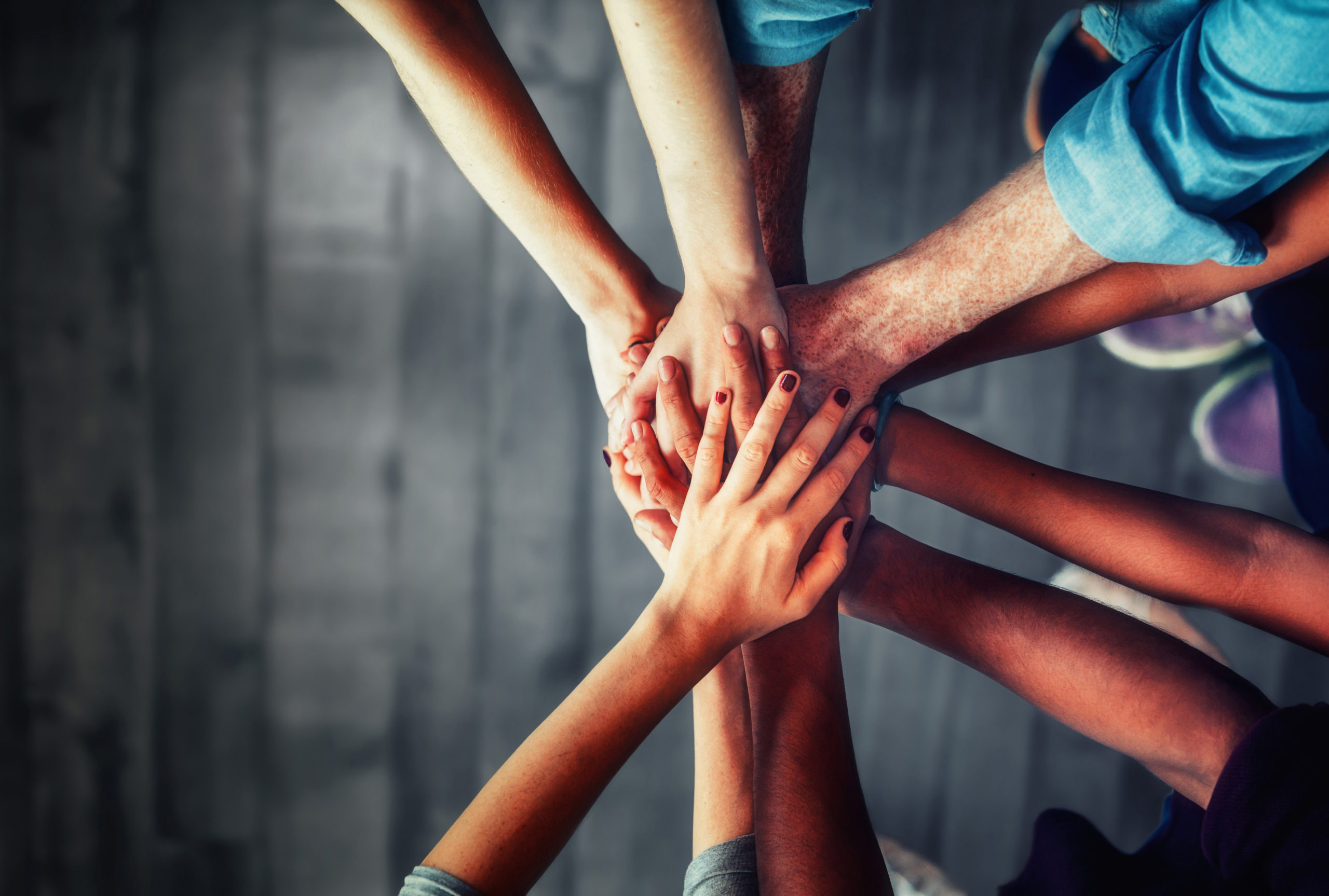 Close up top view of young business people putting their hands t